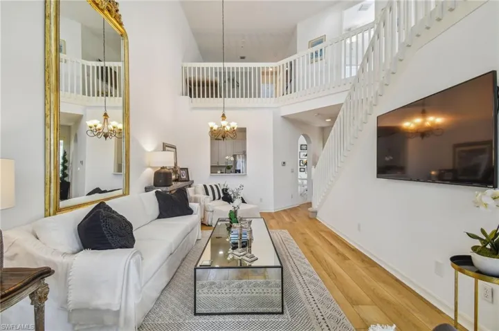 Living room with a high ceiling, light hardwood / wood-style floors, and a chandelier