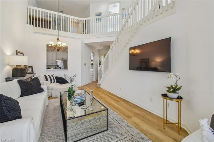 Living room featuring a towering ceiling, an inviting chandelier, and light hardwood / wood-style floors