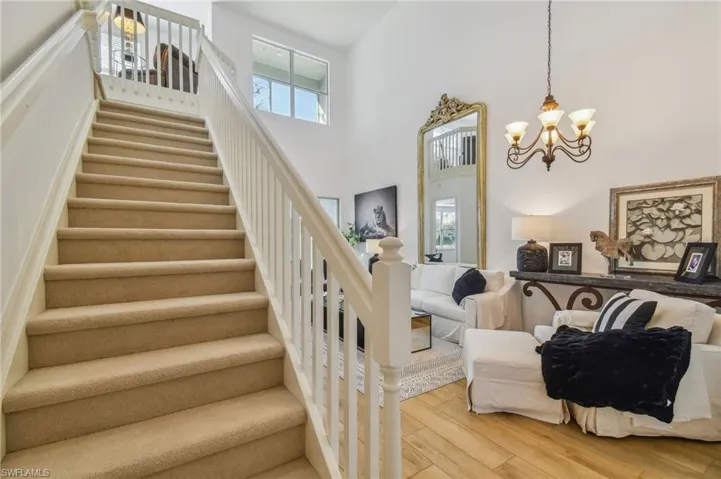 Stairs featuring a towering ceiling, hardwood / wood-style floors, and a chandelier