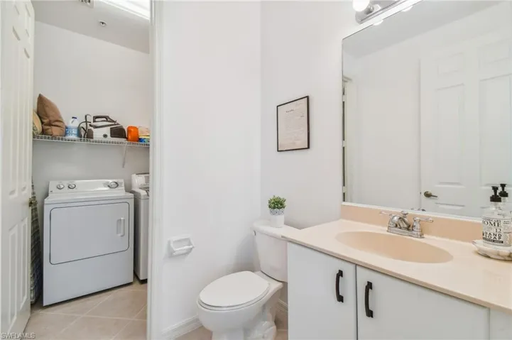 Bathroom featuring vanity, toilet, washing machine and clothes dryer, and tile patterned flooring
