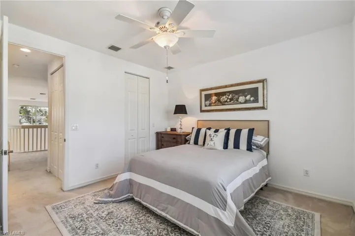 Bedroom with light colored carpet, ceiling fan, and a closet