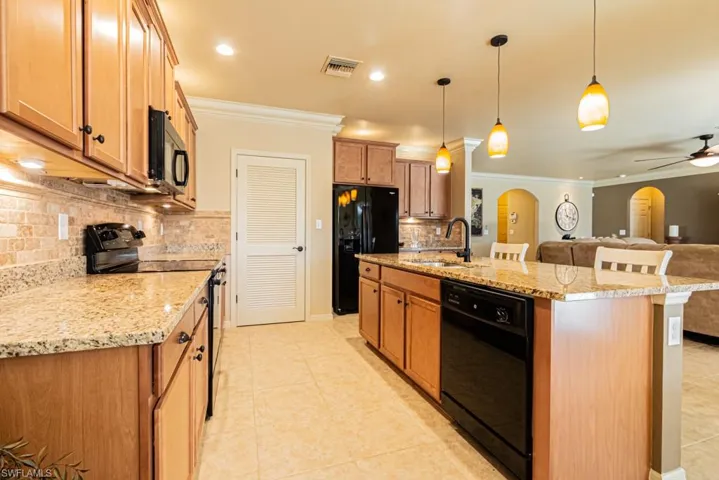 Kitchen with pendant lighting, sink, black appliances, and ornamental molding