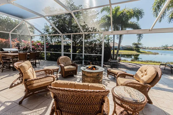 View of patio featuring glass enclosure, a water view, and a fire pit