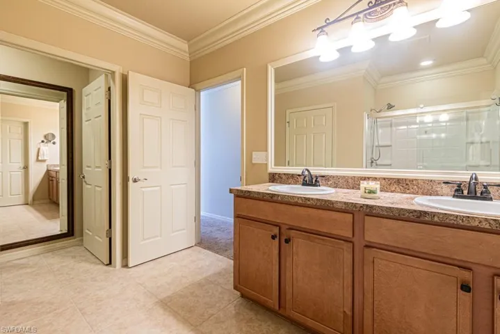 Bathroom with ornamental molding, vanity, tile patterned floors, and a shower with shower door