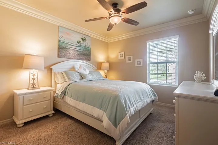 Carpeted bedroom with ceiling fan and ornamental molding