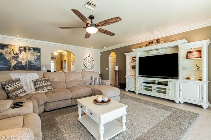 Living room featuring ornamental molding, ceiling fan, and tile patterned floors