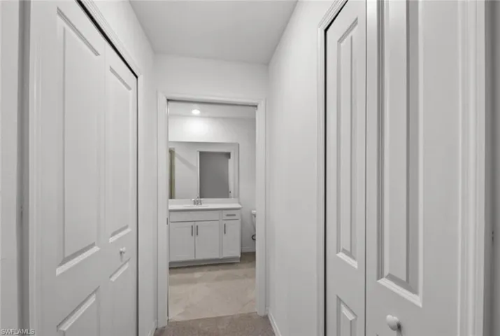 Hall with light colored carpet and a sink