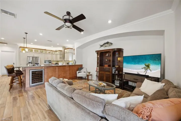 Living room with beverage cooler, ceiling fan, light hardwood / wood-style floors, and crown molding