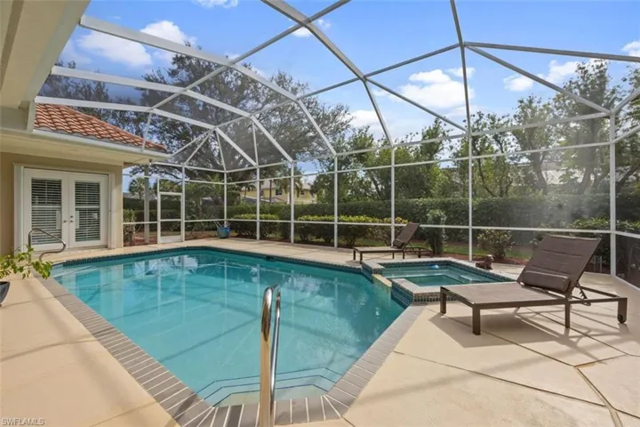 View of pool featuring a patio area, an in ground hot tub, and glass enclosure