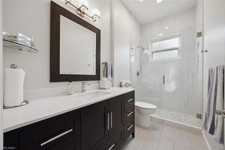 Bathroom with toilet, tile patterned floors, a shower with shower door, and vanity