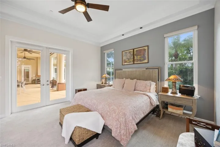Bedroom with light carpet, french doors, multiple windows, ceiling fan, and access to exterior
