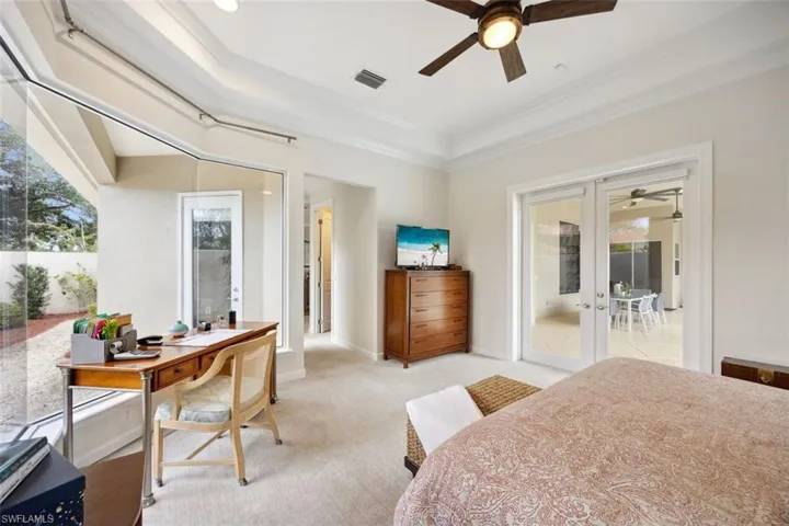 Carpeted bedroom featuring crown molding, ceiling fan, french doors, a tray ceiling, and access to outside