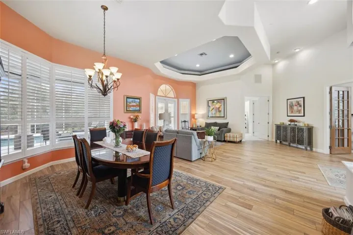 Dining space with a high ceiling, an inviting chandelier, and light hardwood / wood-style tile flooring