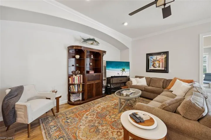 Living room with ornamental molding, ceiling fan, and hardwood / wood-style tile flooring