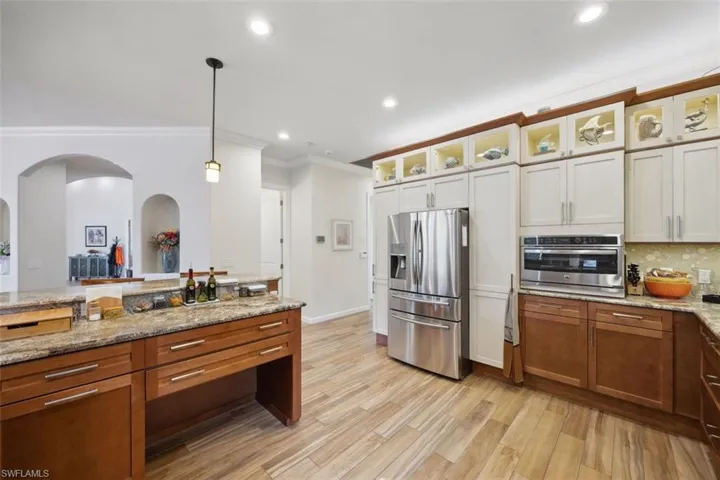 Kitchen with stainless steel appliances, white cabinetry, crown molding, and hanging light fixtures