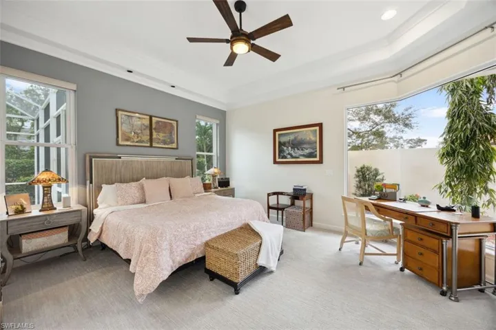 Bedroom with ceiling fan, light colored carpet, multiple windows, and crown molding
