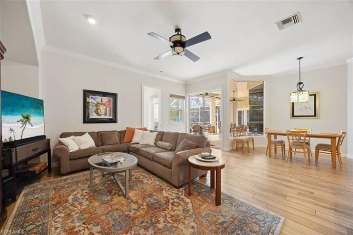 Living room featuring ceiling fan, light wood-type flooring, and ornamental molding