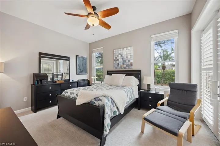 Carpeted bedroom featuring multiple windows and ceiling fan