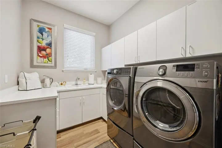 Laundry room featuring sink, cabinets, light wood-type flooring, and washing machine and dryer