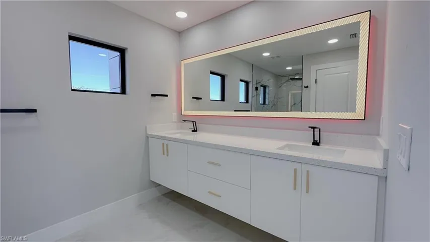 Bathroom featuring a shower with door, vanity, and tile patterned floors