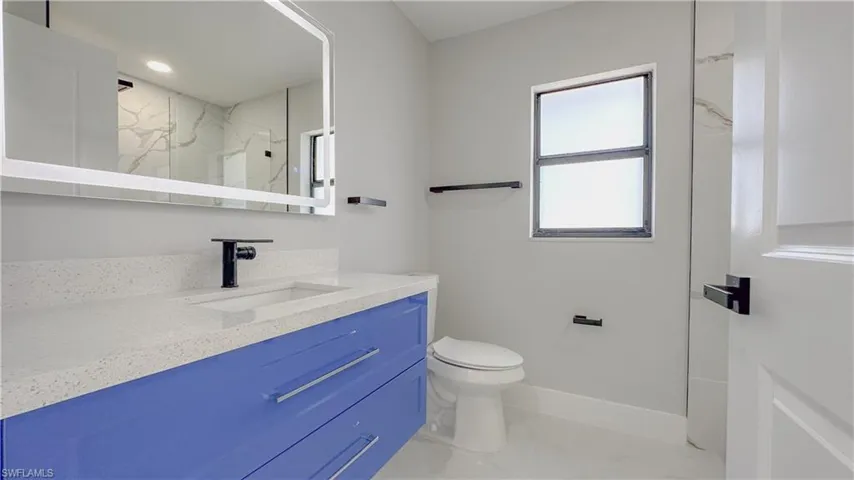 Bathroom with tile patterned flooring, toilet, a tile shower, and vanity