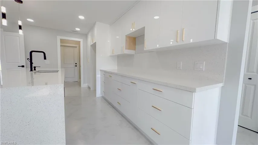 Kitchen featuring white cabinets, decorative backsplash, light tile patterned flooring, and pendant lighting