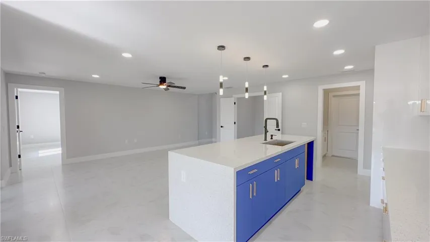 Kitchen with decorative light fixtures, sink, a kitchen island with sink, ceiling fan, and blue cabinets