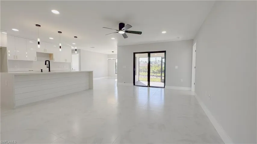 Unfurnished living room featuring light tile patterned floors, sink, and ceiling fan