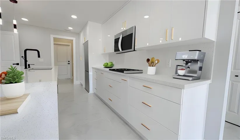 Kitchen with light tile patterned flooring, backsplash, black electric stovetop, decorative light fixtures, and white cabinetry