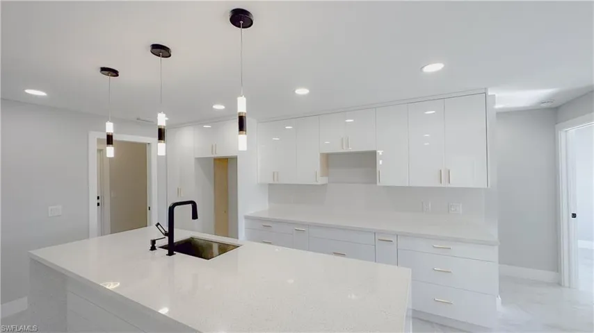 Kitchen with light tile patterned flooring, sink, decorative backsplash, light stone countertops, and hanging light fixtures