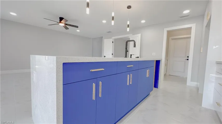 Kitchen featuring decorative light fixtures, blue cabinetry, light tile patterned floors, a kitchen island, and ceiling fan