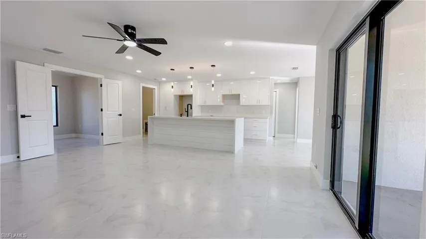 Unfurnished living room featuring ceiling fan, sink, and light tile patterned floors