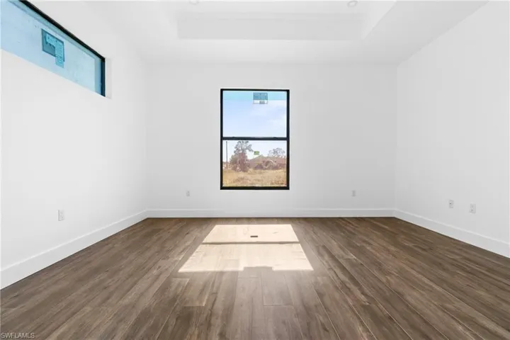 Unfurnished room featuring a tray ceiling and dark wood-type flooring