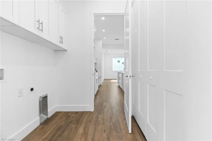 Clothes washing area with cabinets, dark hardwood / wood-style floors, and hookup for an electric dryer