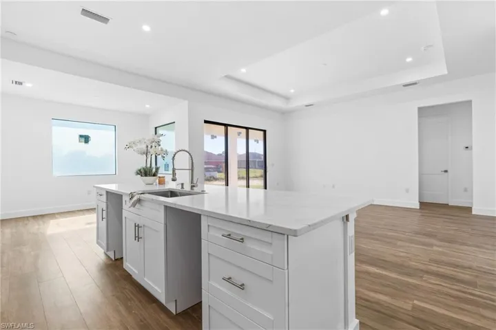 Kitchen featuring white cabinets, dark hardwood / wood-style floors, sink, and a kitchen island with sink