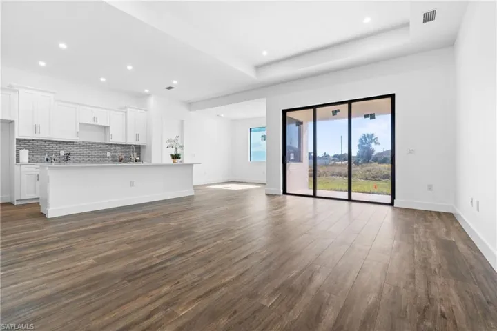 Unfurnished living room with dark hardwood / wood-style flooring and a raised ceiling