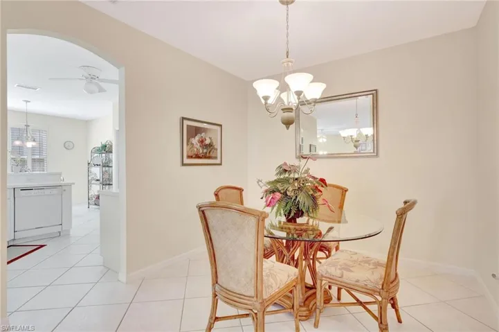 Dining space with light tile patterned flooring, baseboards, arched walkways, and ceiling fan with notable chandelier