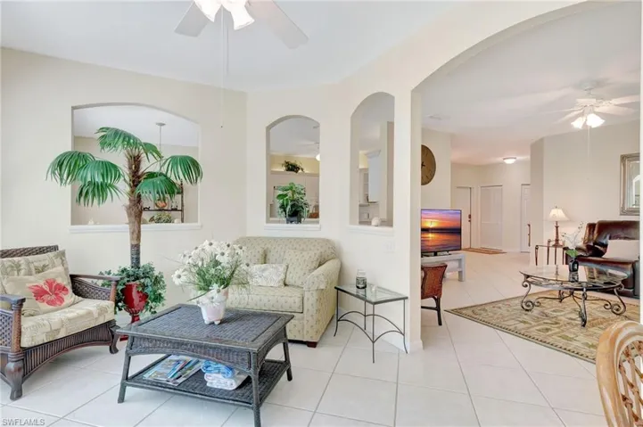 Tiled living area featuring a ceiling fan and arched walkways