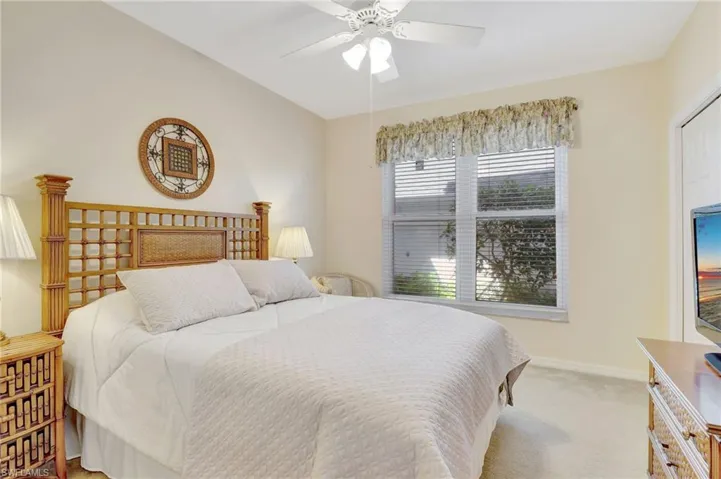 Bedroom featuring light colored carpet, ceiling fan, and baseboards
