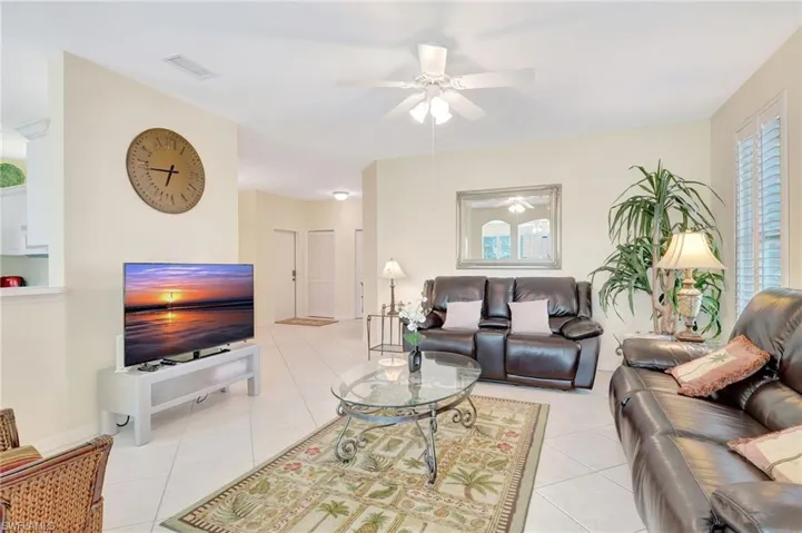 Living area featuring a ceiling fan, light tile patterned floors, and visible vents