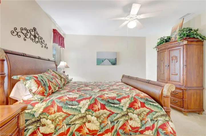 Bedroom with ceiling fan, visible vents, and light carpet