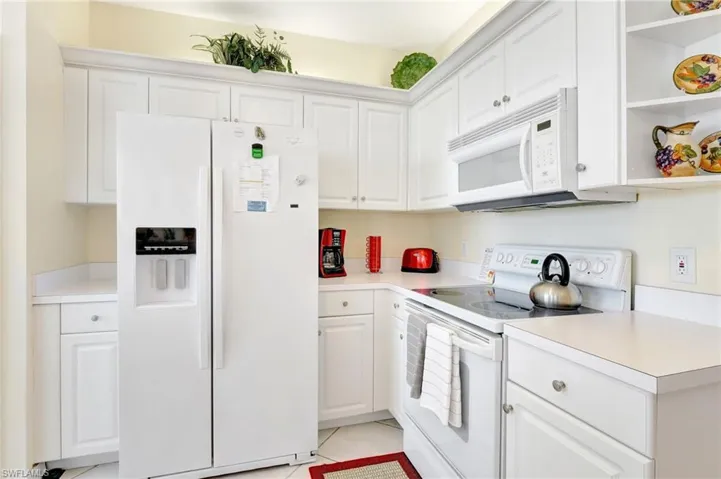 Kitchen with light tile patterned flooring, light countertops, white appliances, white cabinetry, and open shelves
