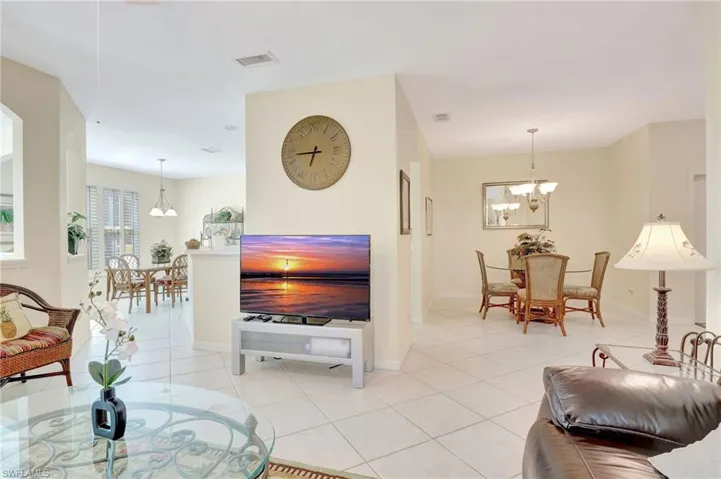 Living area with light tile patterned flooring, baseboards, a chandelier, and visible vents