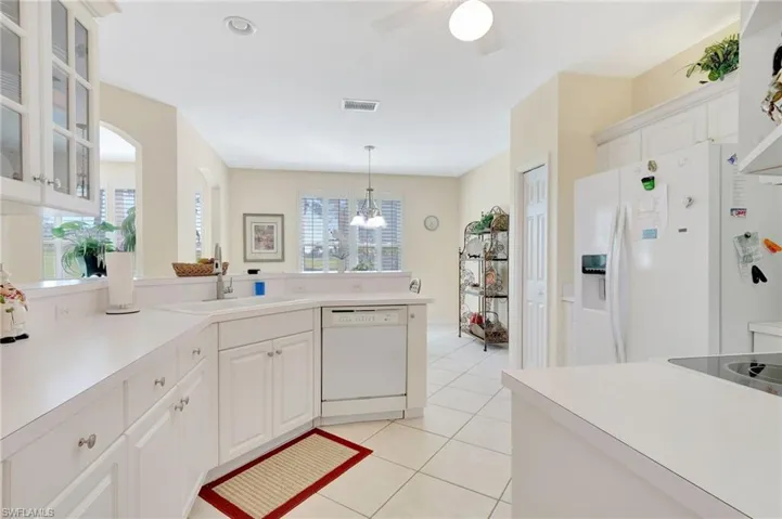 Kitchen featuring light tile patterned flooring, a sink, plenty of natural light, white appliances, and visible vents