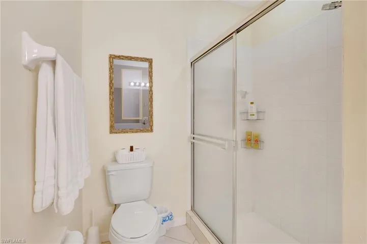 Bathroom with toilet, tile patterned floors, baseboards, and a shower stall