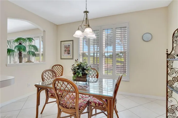 Dining area featuring arched walkways, a wealth of natural light, baseboards, and light tile patterned flooring