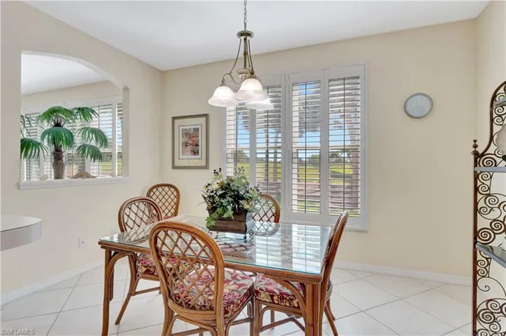 Dining area featuring an inviting chandelier, light tile patterned floors, arched walkways, and baseboards