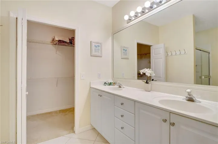 Bathroom with a shower stall, double vanity, a sink, and tile patterned floors