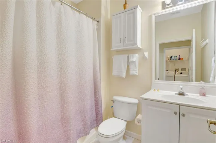 Bathroom featuring washing machine and dryer, visible vents, toilet, and vanity
