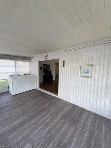 Unfurnished living room with dark wood-type flooring, wood ceiling, and washing machine and clothes dryer